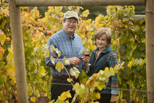 Man and women holding wine glasses in a vineyard